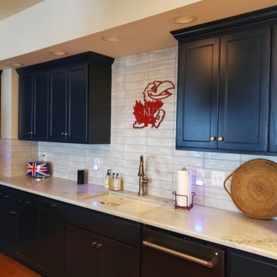 off white tile backsplash with navy blue cabinets and slab countertops